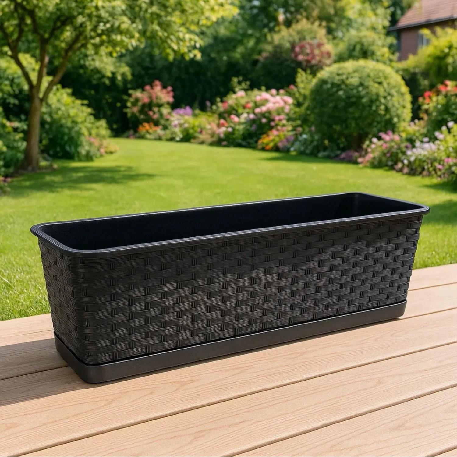 Anthrazitfarbener Blumenkasten 80 cm in Rattan-Optik mit Untersetzer auf Holzterrasse. Ideal für Balkon & Garten.