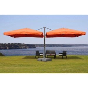 Großer terracotta Doppel-Ampelschirm mit Ständer über Sitzgruppe auf grüner Wiese am Meer. Windstabiler Sonnenschirm für Garten & Terrasse.