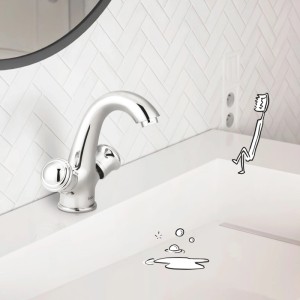 Glänzende baliv Zweigriff-Waschtischarmatur in Chrom auf weißem Waschbecken. Eine Zahnbürste und Spritzer beleben die Szene.