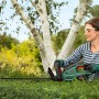 Frau schneidet Hecke mit Bosch Akku-Heckenschere UniversalHedgeCut 18-55. Kabellose Heckenschere im Einsatz.