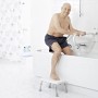 Mann steigt mit Ridder WC-Aufstehbügel und Tritthocker in Badewanne. Sicherheit im Bad.