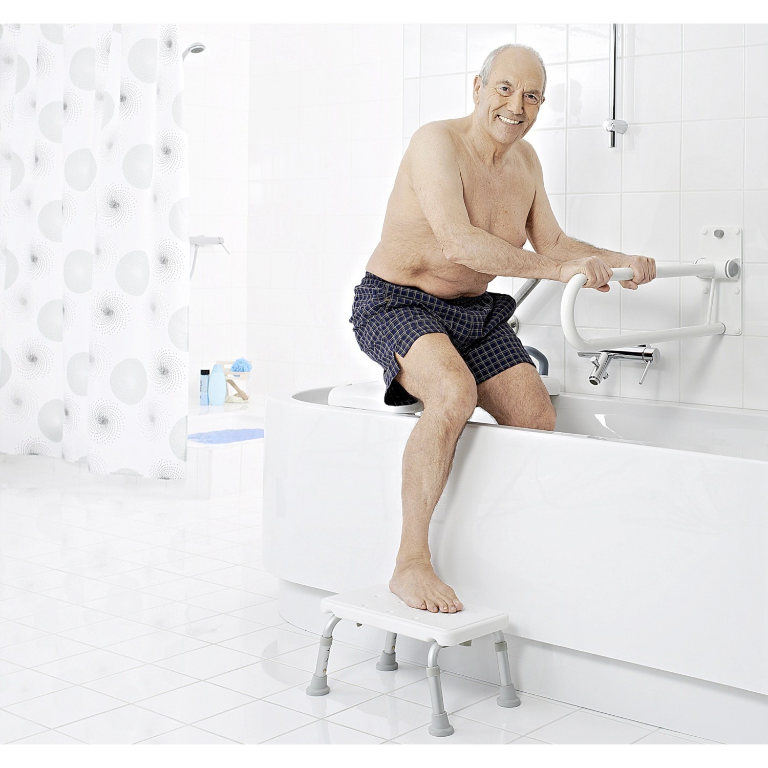 Mann steigt mit Ridder WC-Aufstehbügel und Tritthocker in Badewanne. Sicherheit im Bad.