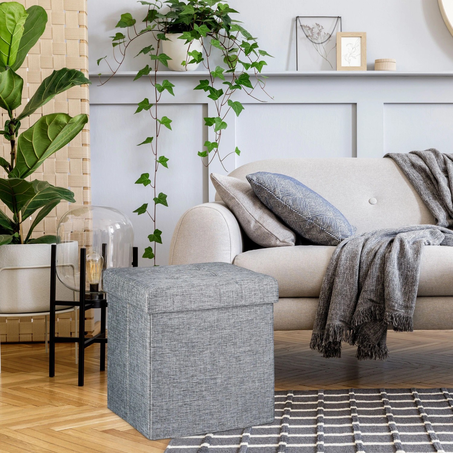 Grauer Leinen-Sitzhocker mit Stauraum, faltbar, gepolstert. Praktischer Hocker im Wohnzimmer neben Sofa.