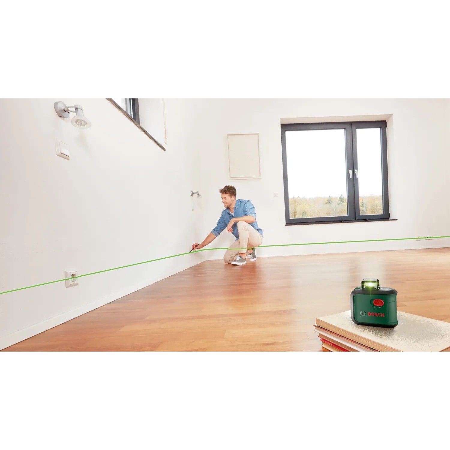 Bosch AdvancedLevel 360 Kreuzlinienlaser im Einsatz: Mann richtet grüne Laserlinie an Wand aus.