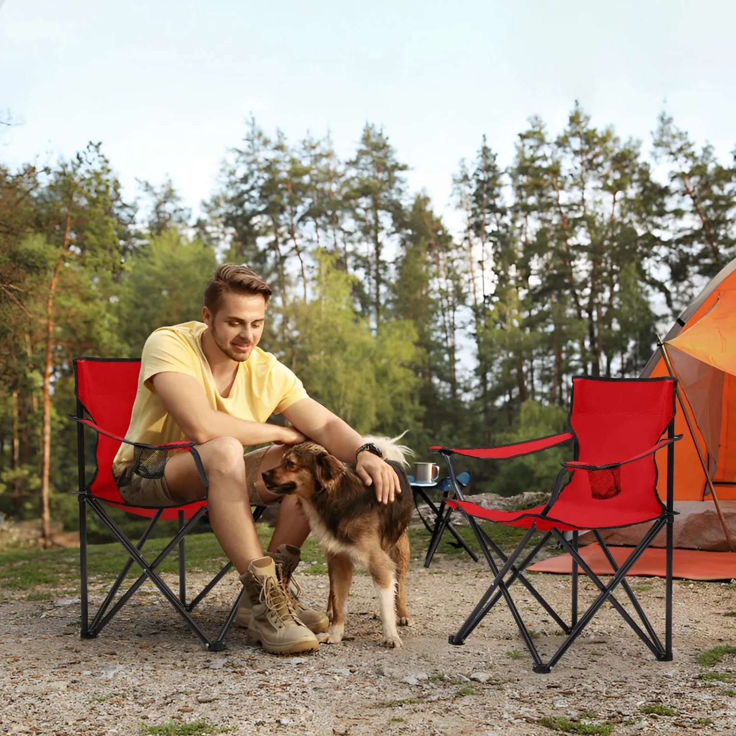 Zwei rote Campingstühle Sunula mit Mann und Hund beim Camping.