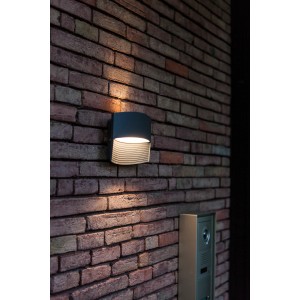 Moderne Lutec LED-Außenwandleuchte Lotus in Anthrazit mit Up & Down Lichteffekt an einer Backsteinwand.