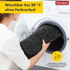 Waschbare, anthrazitfarbene Floordirekt Badematte Nasa wird in eine Waschmaschine gelegt.