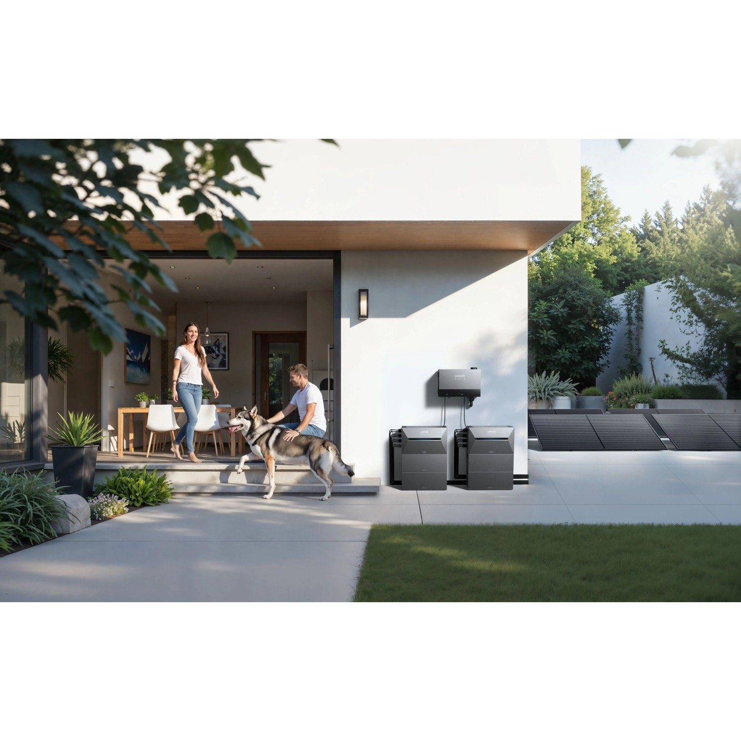 Anker Solix Solarbank mit Power Dock und Solarmodulen am Haus, Paar mit Hund im Vordergrund.