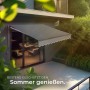 Ausgefahrene, dunkelgraue Gelenkarmmarkise von Tectake spendet Schatten auf Terrasse.