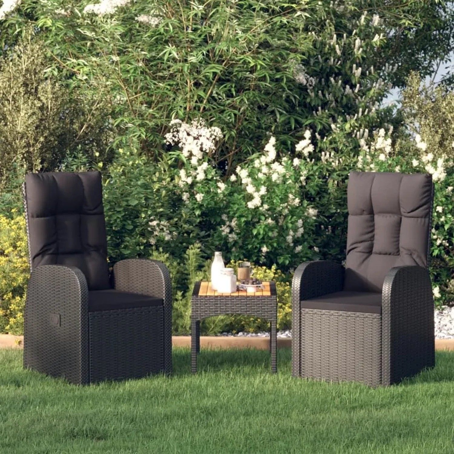 2 schwarze Gartenliegen aus Rattan mit Auflagen im Garten.
