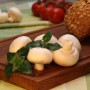Frisches Bio-Pilzkraut (Rungia) auf Holzbrett mit Champignons, Tomaten und Brot.