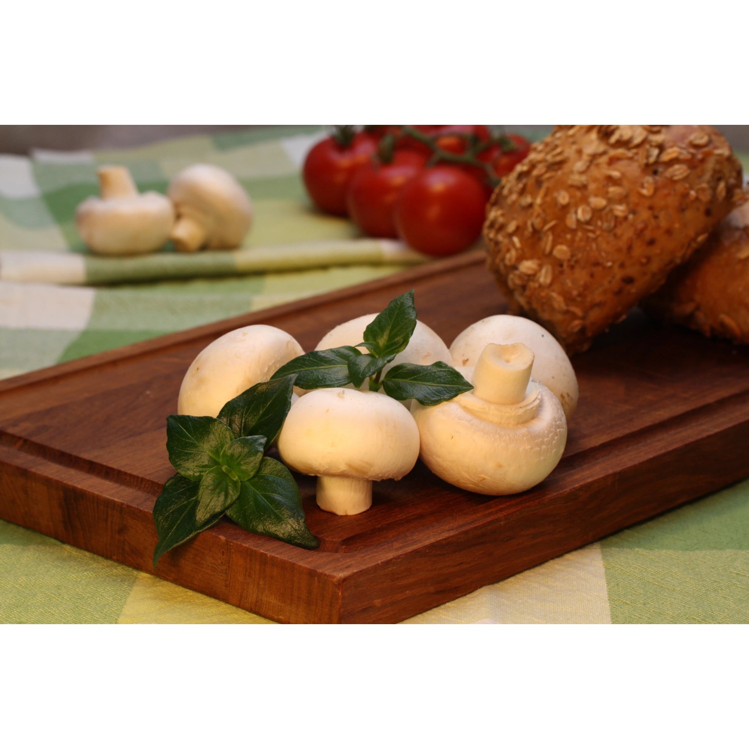 Frisches Bio-Pilzkraut (Rungia) auf Holzbrett mit Champignons, Tomaten und Brot.