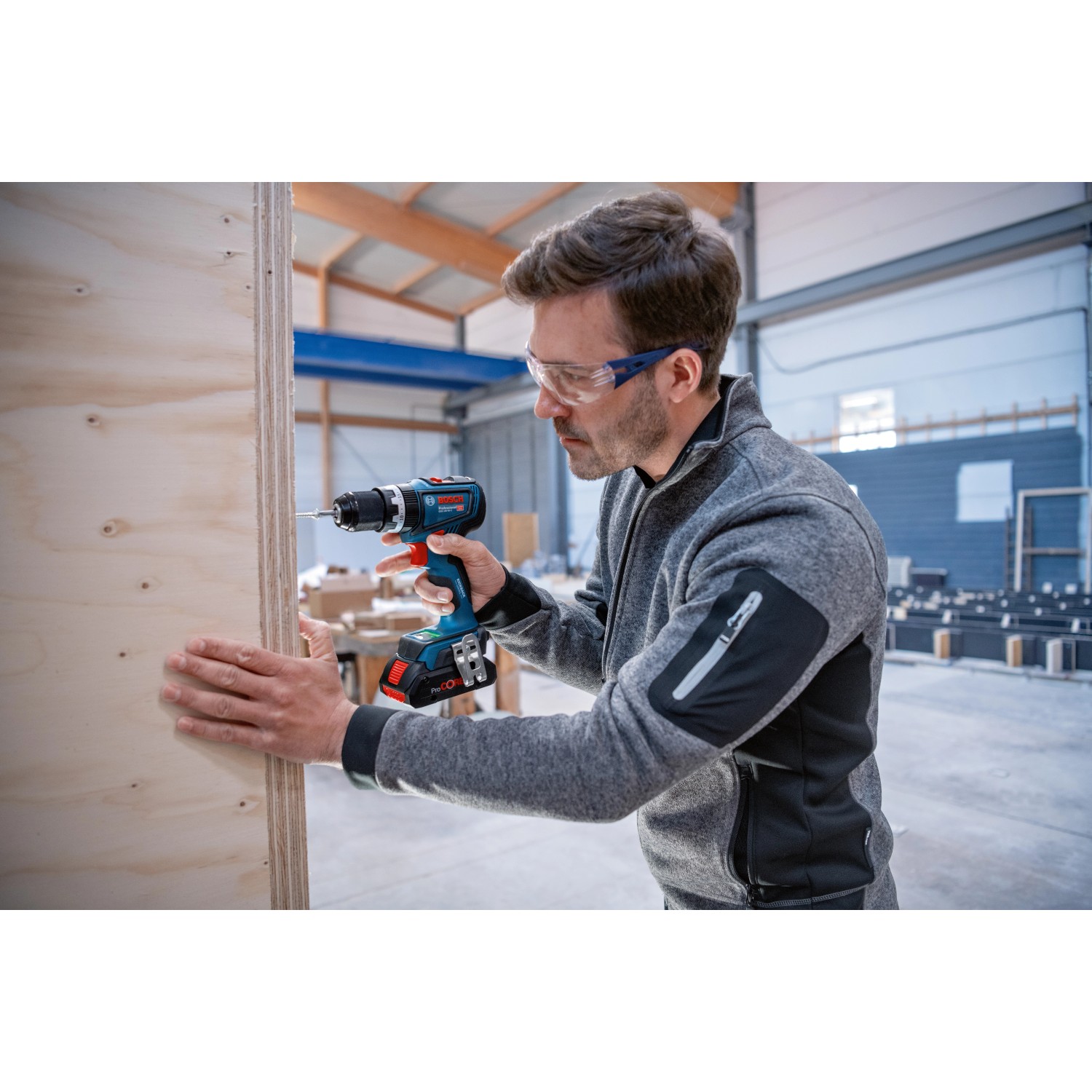 Mann schraubt mit Bosch Professional Akku-Schlagbohrschrauber GSB 18V-90 C in Holz.