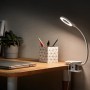 Philips Forys LED-Tischleuchte mit Clip und Akku auf Schreibtisch, Licht an.