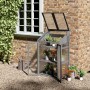 Outsunny Gewächshaus aus Tannenholz, grau, mit Regalen und geöffneter Tür vor einer Ziegelwand.