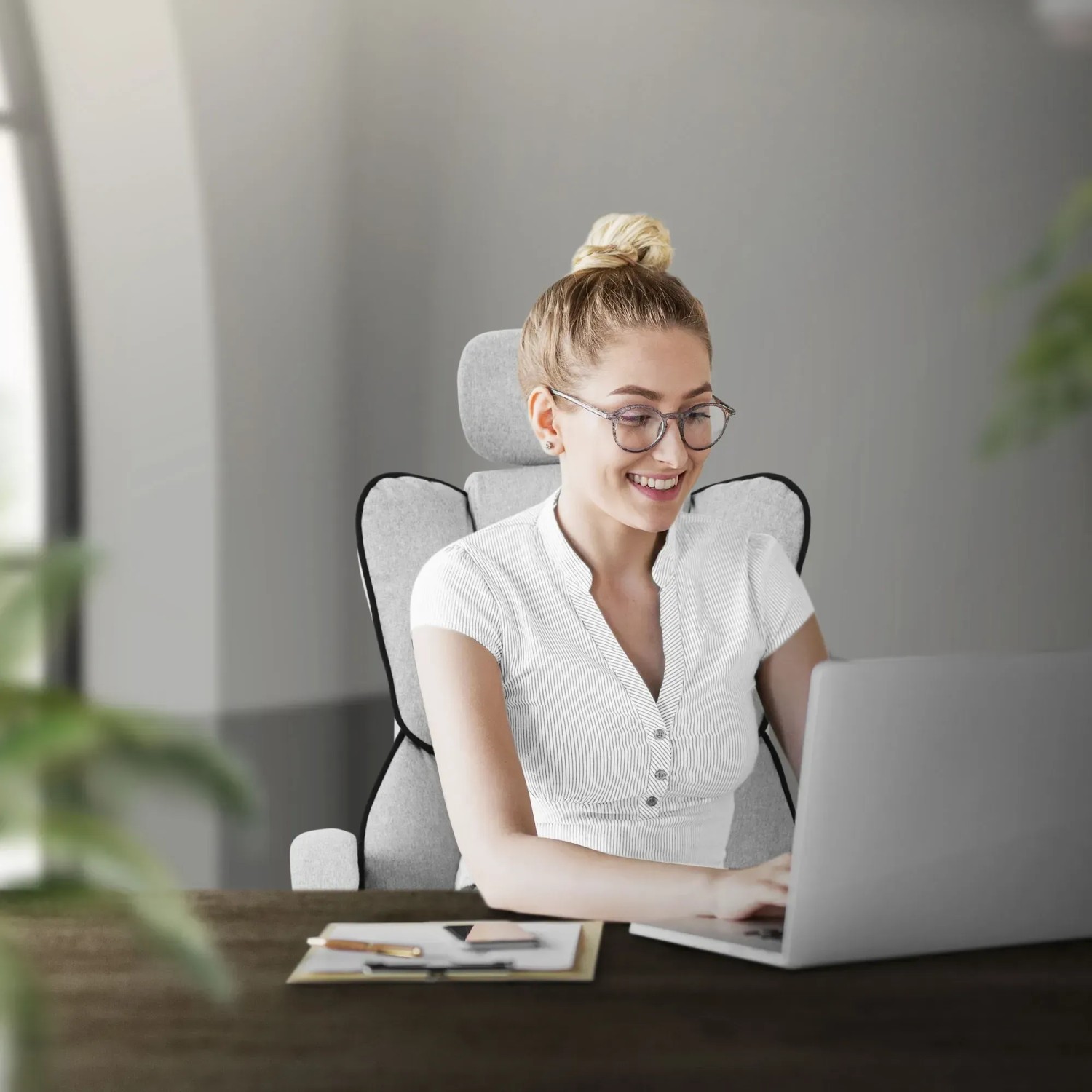 Frau sitzt auf hellgrauem, ergonomischem ML-Design Bürostuhl vor Laptop.