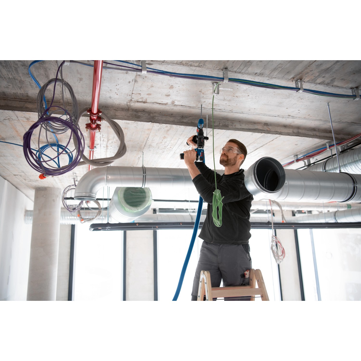 Handwerker bohrt mit Bosch Professional GFA 12-H FlexiClick Bohrhammeraufsatz in Decke.