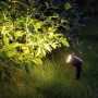 Schwarzer LED's Work Gartenstrahler mit Erdspieß beleuchtet einen Busch im Garten.