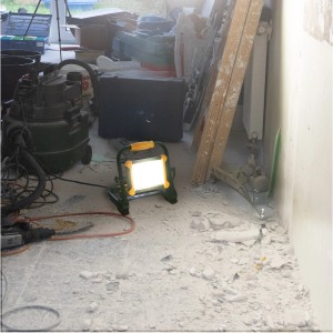 LED Arbeitsleuchte in Schwarz-Gelb leuchtet auf Baustelle. Kompakte Baulampe für den Innenbereich.