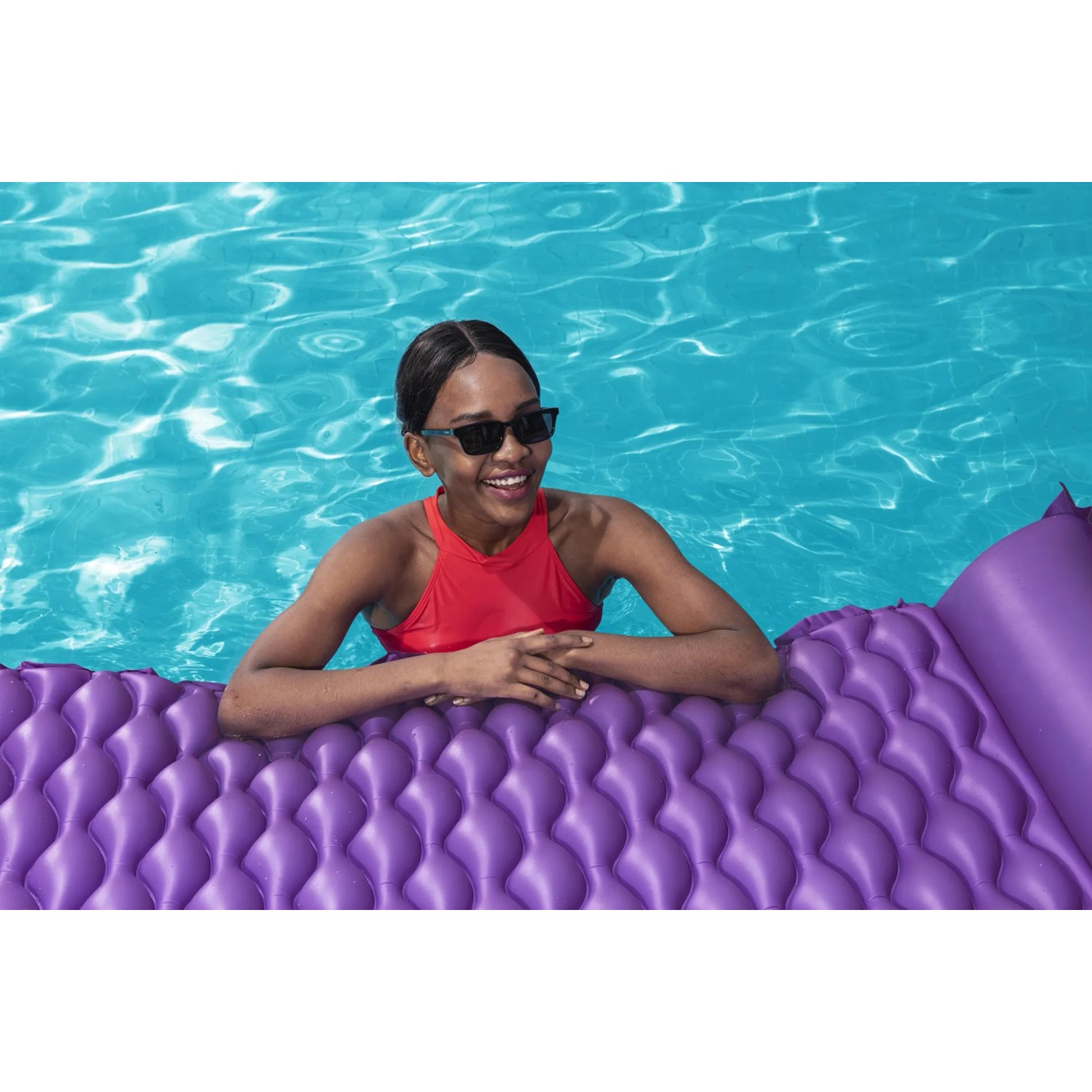 Frau entspannt auf lila Bestway Luftmatratze Float'n Roll im Pool.