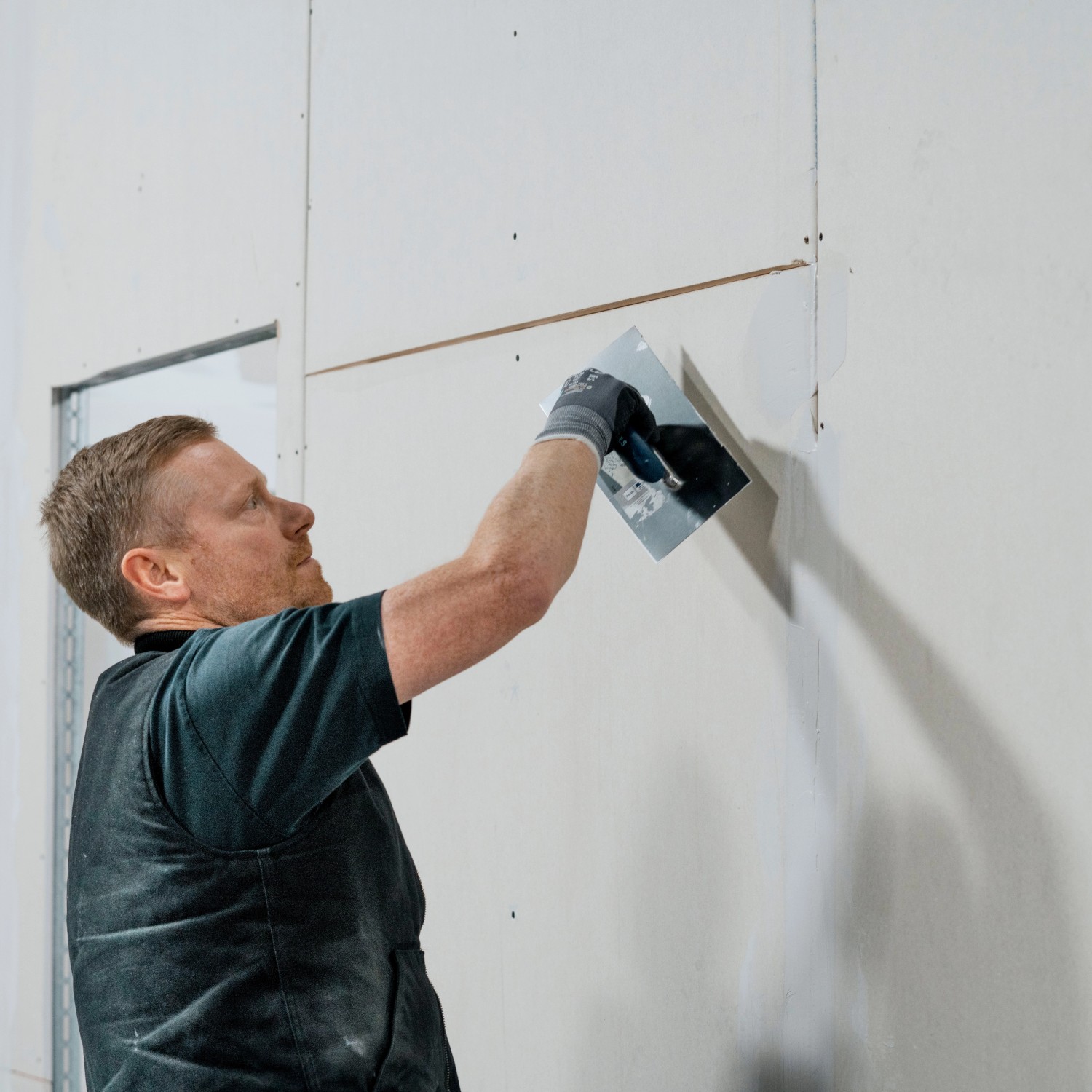 Handwerker beim Auftragen von Knauf Uniflott Finish Feinspachtel auf eine Gipskartonwand.