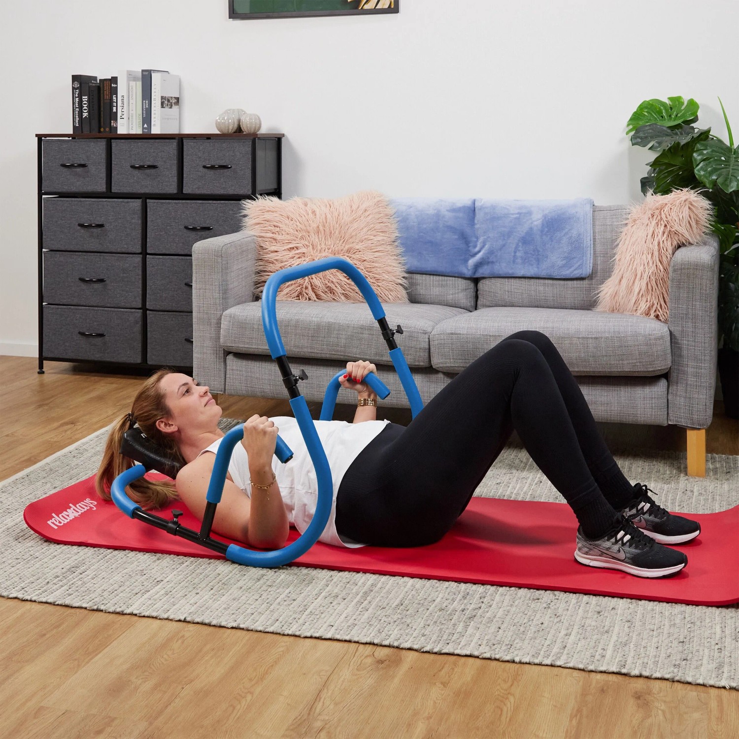 Frau nutzt blauen Relaxdays Bauchtrainer AB Roller auf roter Matte. Ergonomisches Fitnessgerät für effektives Bauchmuskeltraining zu Hause.