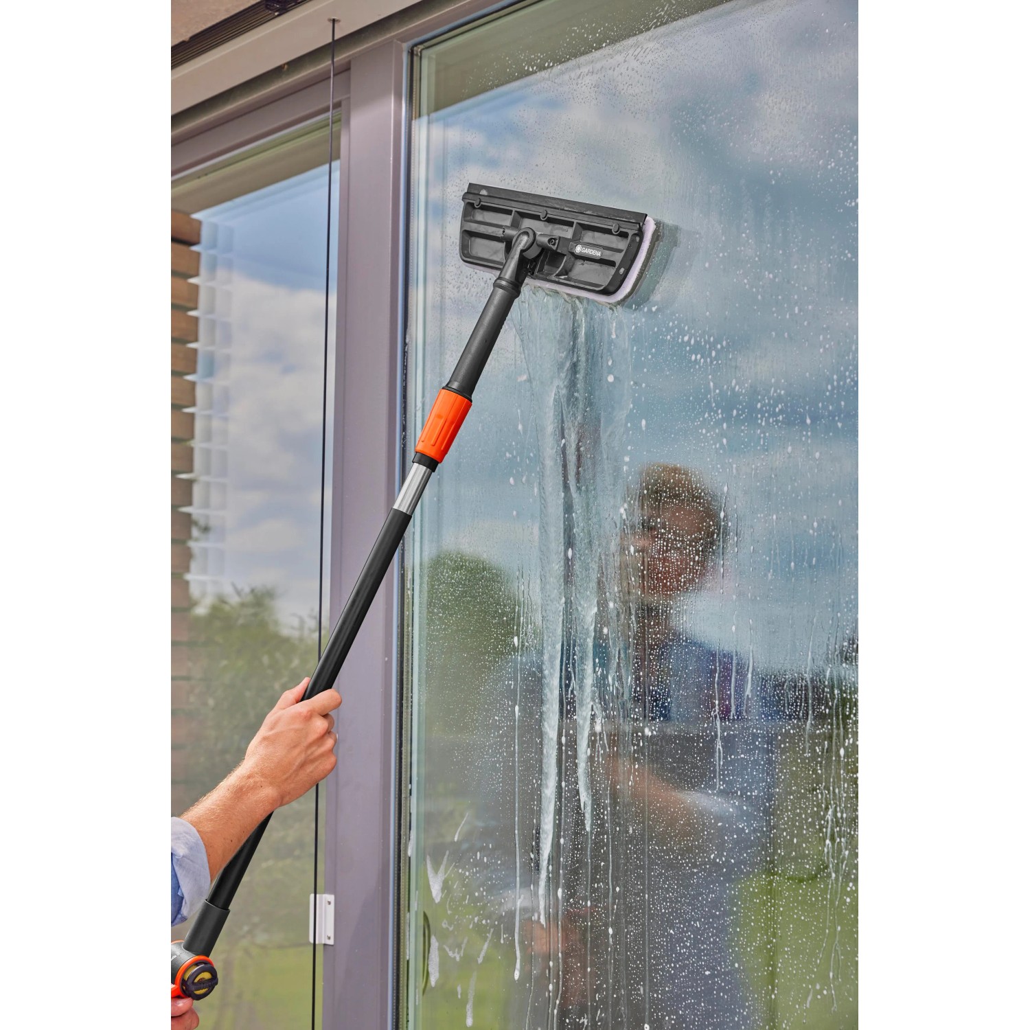 Gardena Cleansystem Fensterwischer mit Stiel und Mikrovlies im Einsatz zur Fensterreinigung.