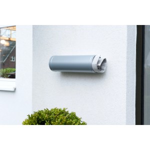 Graues Tesa Powerbond Montageband Outdoor an einer weißen Wand mit Zeitung darin.