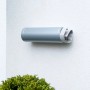 Graues Tesa Powerbond Montageband Outdoor an einer weißen Wand mit Zeitung darin.