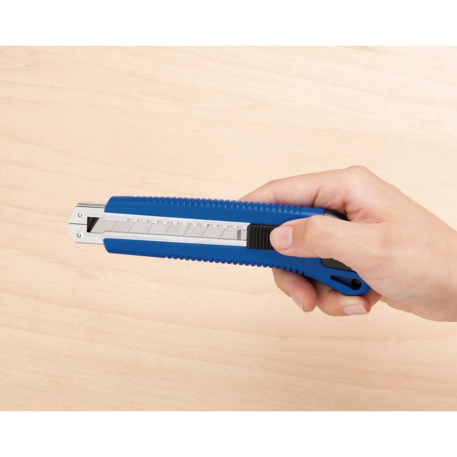 Hand hält blaues LUX Cuttermesser Classic 100 mm vor hellem Holzgrund.