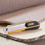 Stanley FatMax Cuttermesser 18mm, schwarz-gelb, mit Abbrechklingen auf Teppich.
