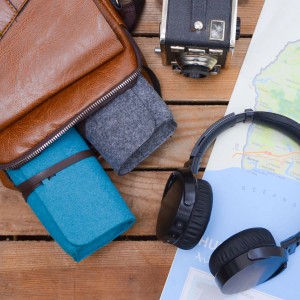 DuneDesign 3er Set Brillenetui aus Filz in Blau, Grau und Anthrazit neben einer Tasche und Kopfhörern.