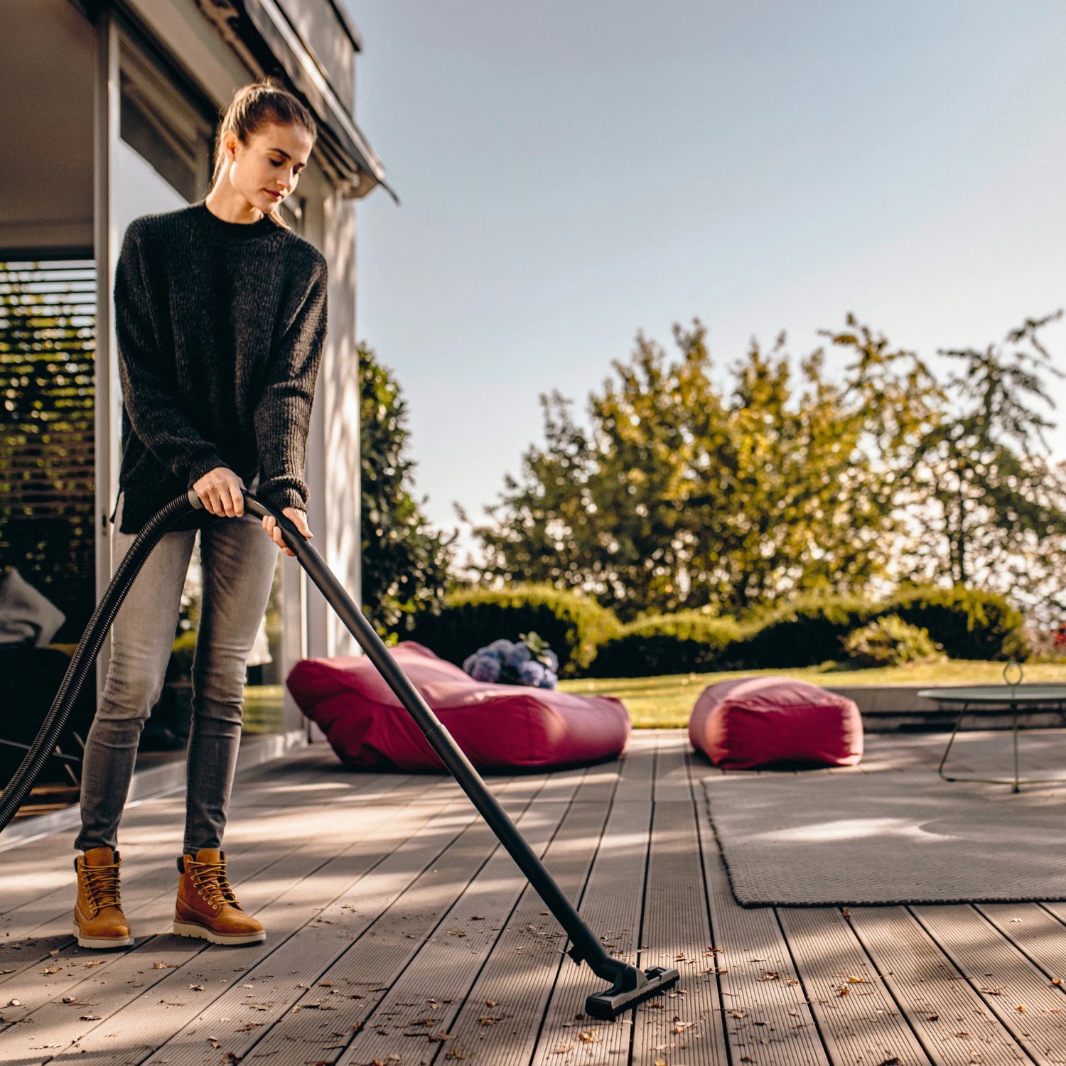 Frau saugt mit Kärcher WD 4 V-20/5/22 Nass-Trockensauger Terrasse. Leistungsstark und effizient.