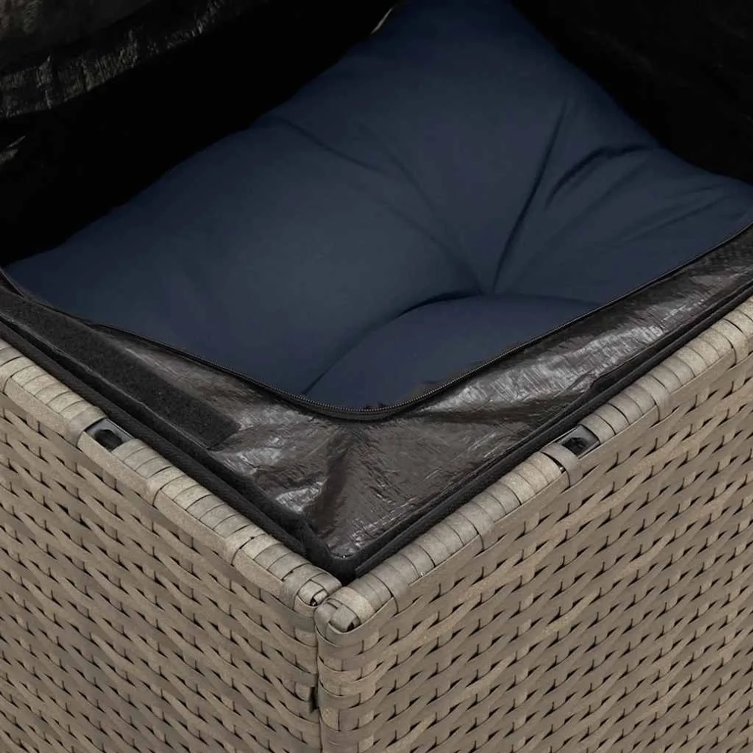 Detailaufnahme: Graue Gartenmöbel-Sofagarnitur aus Rattan mit blauem Kissen und wasserfestem Beutel.