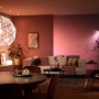 Philips Hue E27 Lampe im Wohnzimmer mit farbiger Beleuchtung.