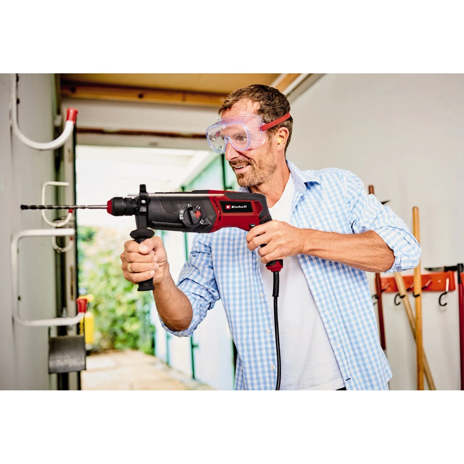 Einhell Bohrhammer TE-RH 950 5F in Aktion: Mann bohrt mit rotem Bohrhammer in Wand. Inkl. Koffer und Tiefenanschlag.