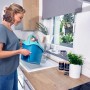 Frau befüllt blauen Leifheit Clean Twist Disc Mop Ergo Eimer am Waschbecken. Reinigungsgeräte Set.