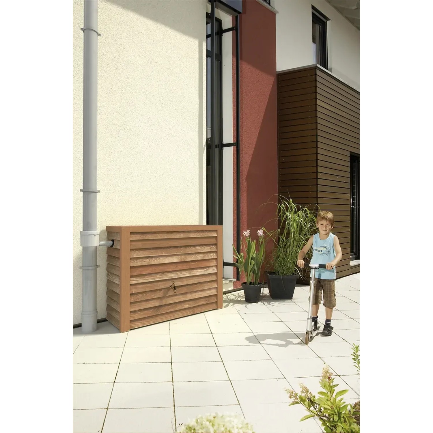 Garantia Regenwasser-Wandtank Woody 350 l Lightwood in Holzoptik vor Hauswand mit Kind auf Roller.