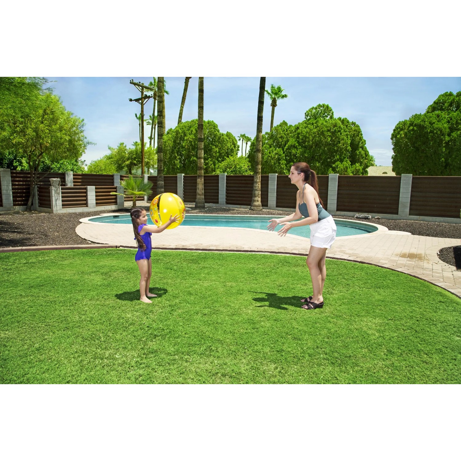 Mädchen spielt mit gelbem Bestway Wasserball im Garten am Pool.