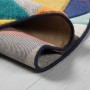 Gerollter Flair Rugs Kinderteppich Rhumba, mehrfarbig mit geometrischen Mustern, blauer Kante auf hellem Holzboden.