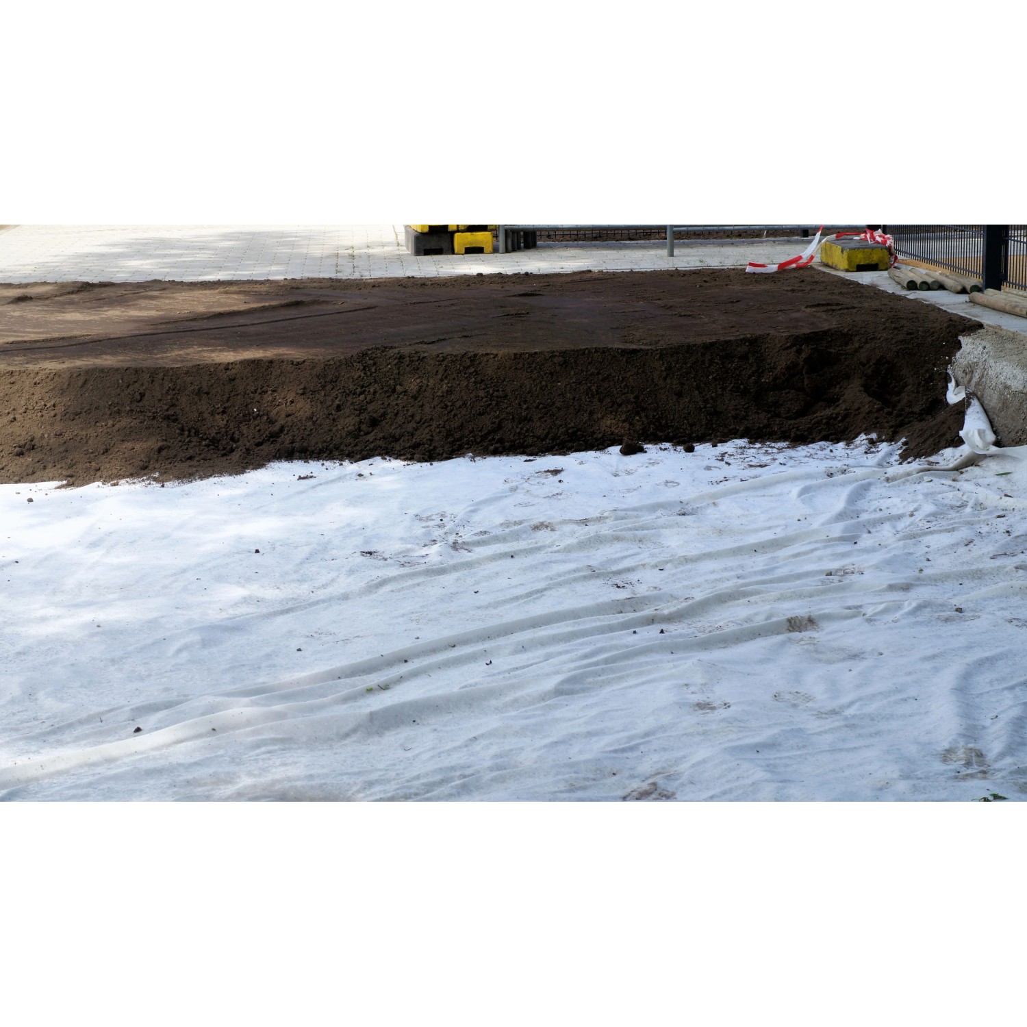 Aquagart Gartenvlies 150g, 25m²: Weißes Unkrautvlies unter dunkler Erde im Garten.