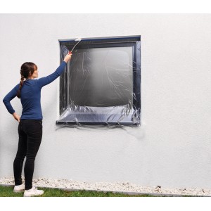 Frau deckt Fenster mit Tesa Abdeckfolie Easy Cover Outdoor ab. Schutz vor Farbe bei Aussenarbeiten.