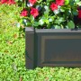 Anthrazitfarbener KHW Pflanzkasten mit Spalier und roten Blüten im Garten.