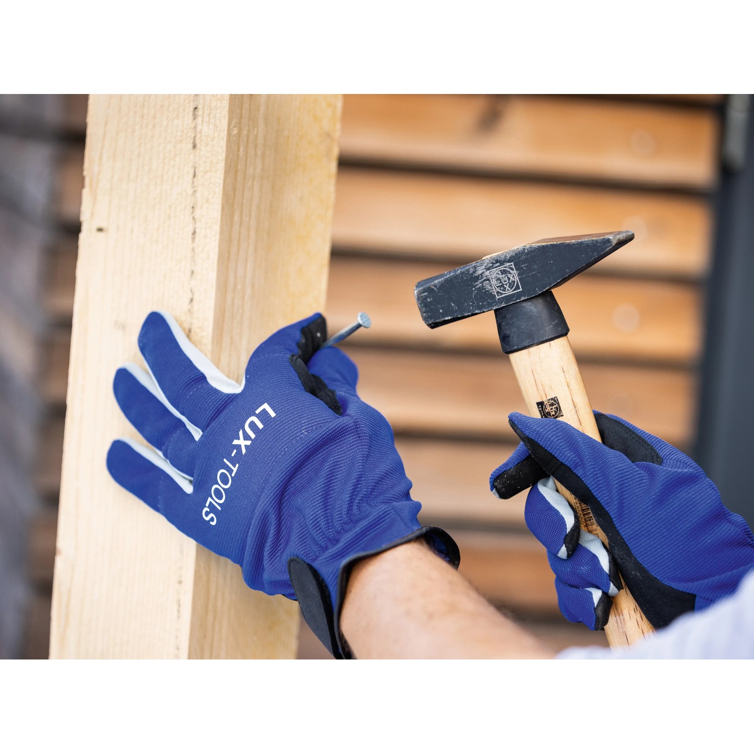 Hände mit LUX Arbeitshandschuhen Tough Gr. 8 beim Hämmern eines Nagels in Holz.