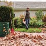 Mann nutzt Stihl Akku-Laubbläser BGA 50 im Garten. Laubkorb und Rechen sind auch zu sehen.