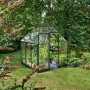 Schwarzes Halls Gewächshaus Qube 66 (3,9 m²) im Garten mit Pflanzen.