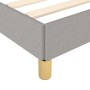 Detailansicht: Hellgraues Stoff-Bettgestell 90x200 mit goldenen Füßen.