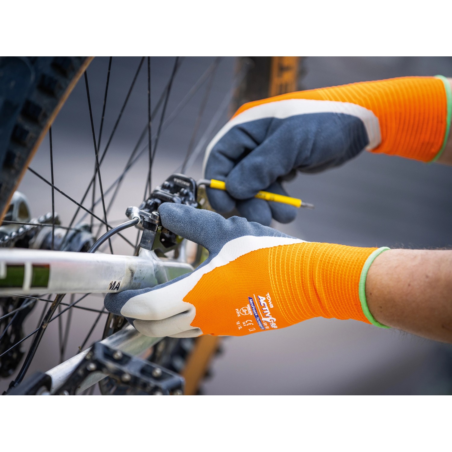 Hände mit LUX Arbeitshandschuhen Super Grip Gr. 9 reparieren ein Fahrrad.
