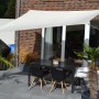 Rechteckiges, helles Sonnensegel über einer Terrasse mit Tisch und Stühlen.