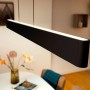 Moderne, schwarze Philips Hue LED-Pendelleuchte Ensis mit Farbwechsel über Esstisch.